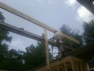 Carpenter setting a ridge beam over a new addition frame — Ice Dam Removal by Roofing Brothers in Udell