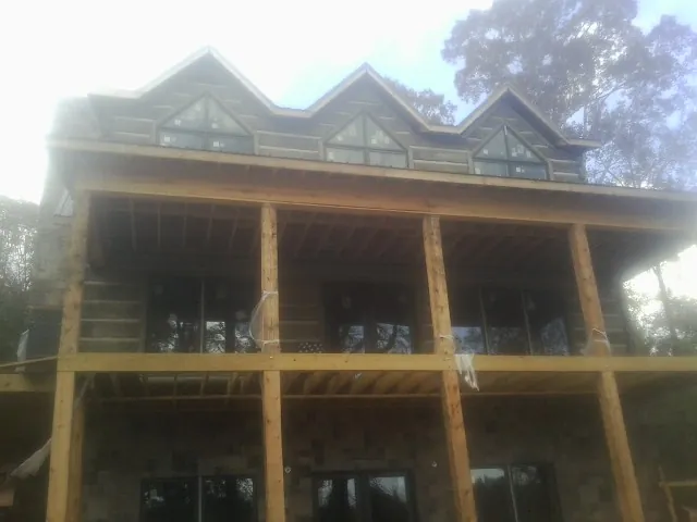 Dormers and porch framing on a large log home under construction — Roof Coating work by our crew in Udell