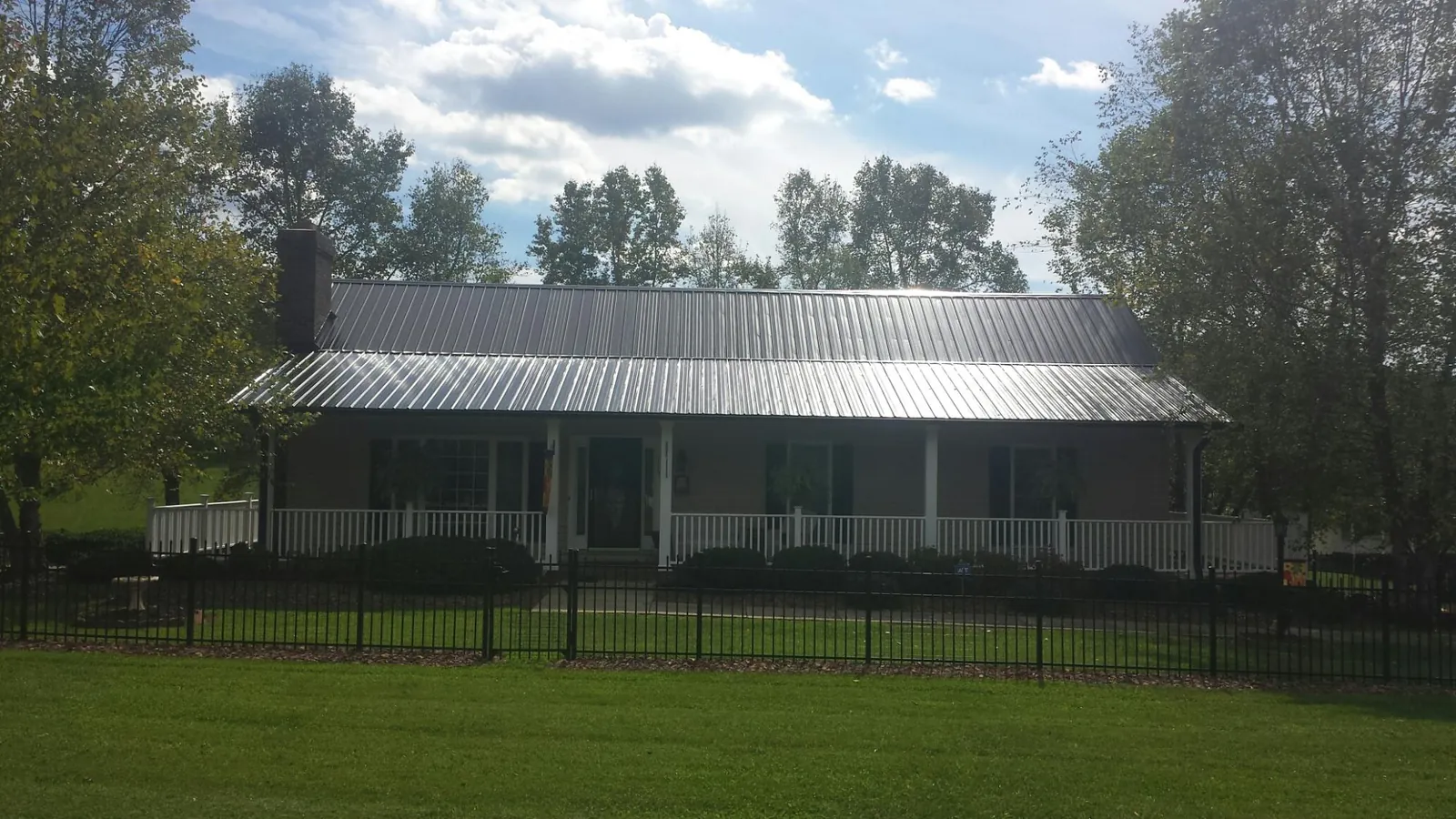 Gray metal roof on a brick ranch with a full width front porch — Gutter Guard Installation work by our crew in Udell